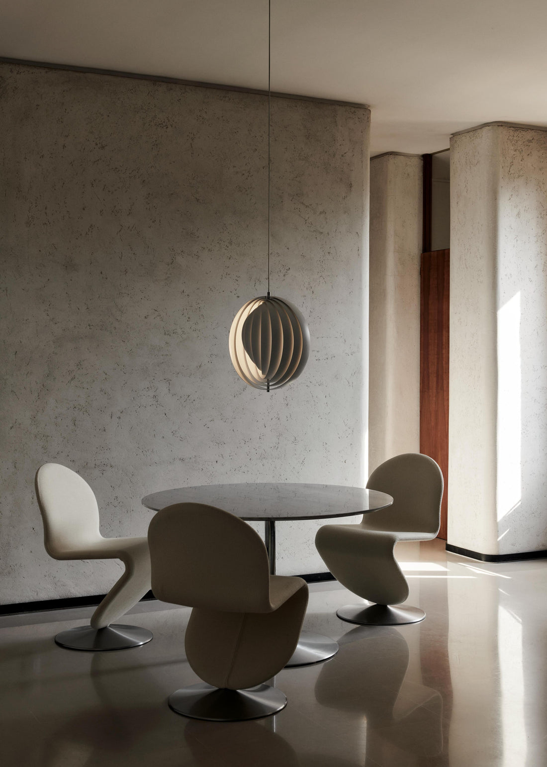 Large white Verner Panton Moon Pendant hanging over a round dining table with white chairs