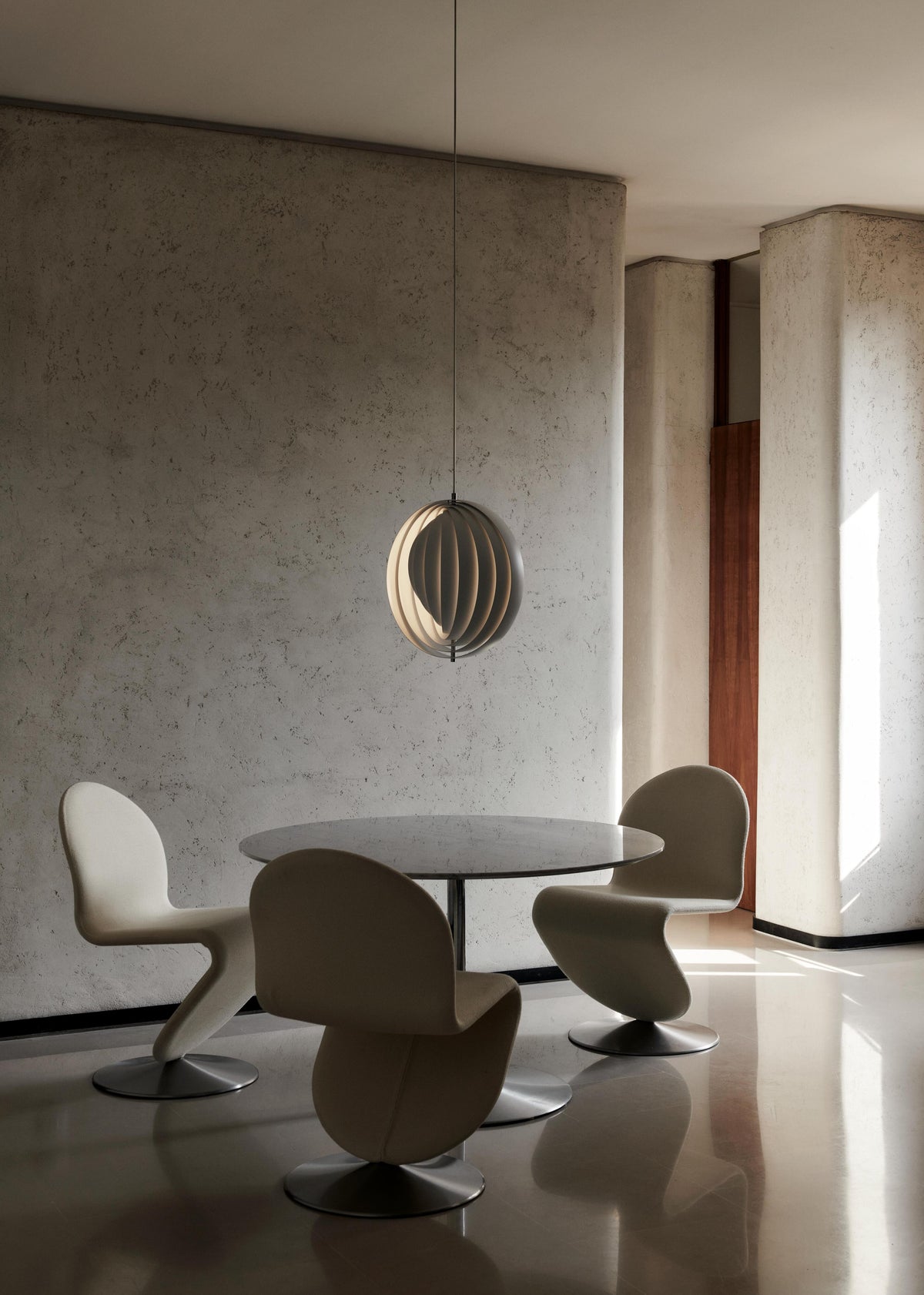 Large white Verner Panton Moon Pendant hanging over a round dining table with white chairs