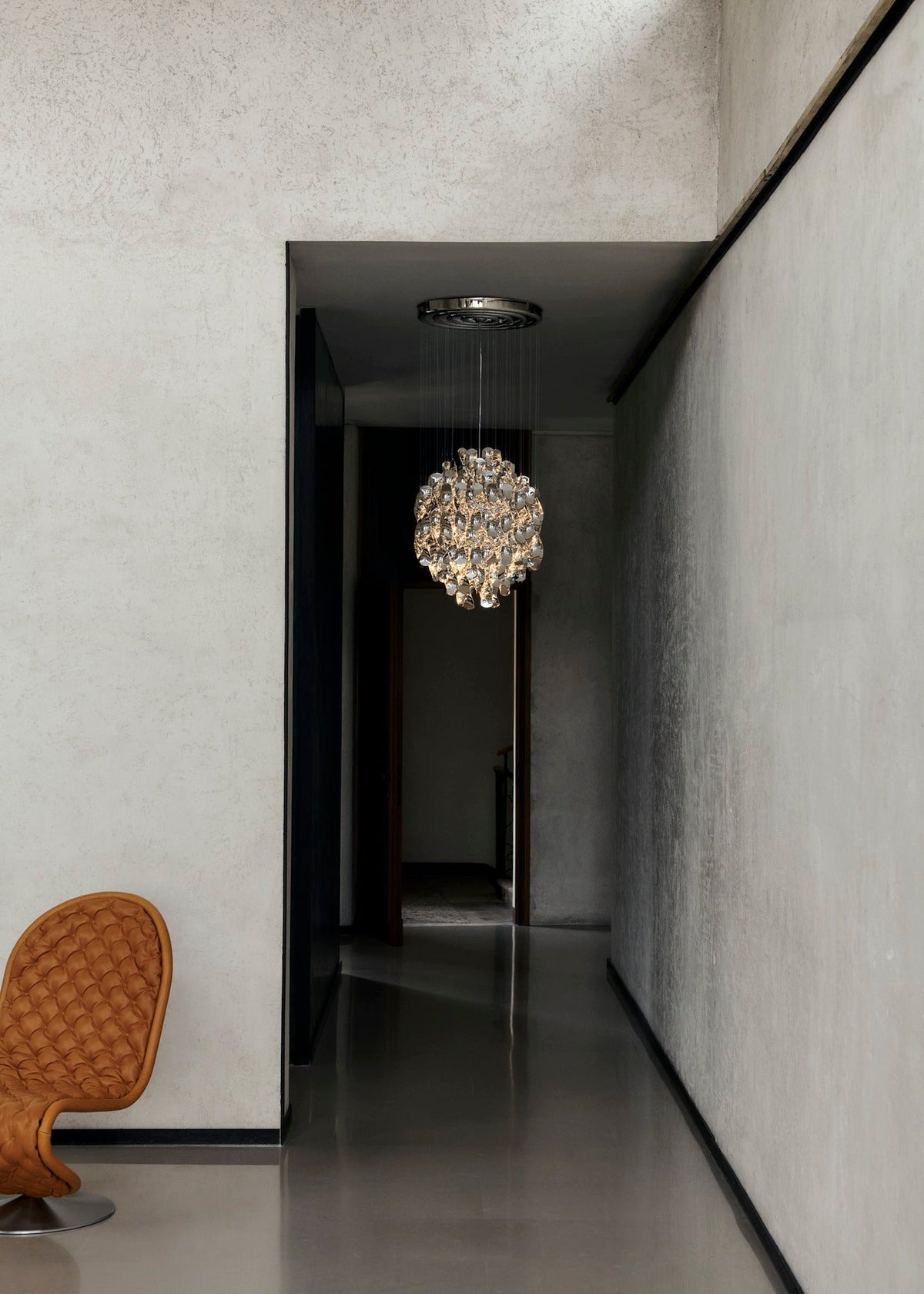 Verner Panton Spiral SP1 pendant in silver hanging in a long, narrow concrete corridor