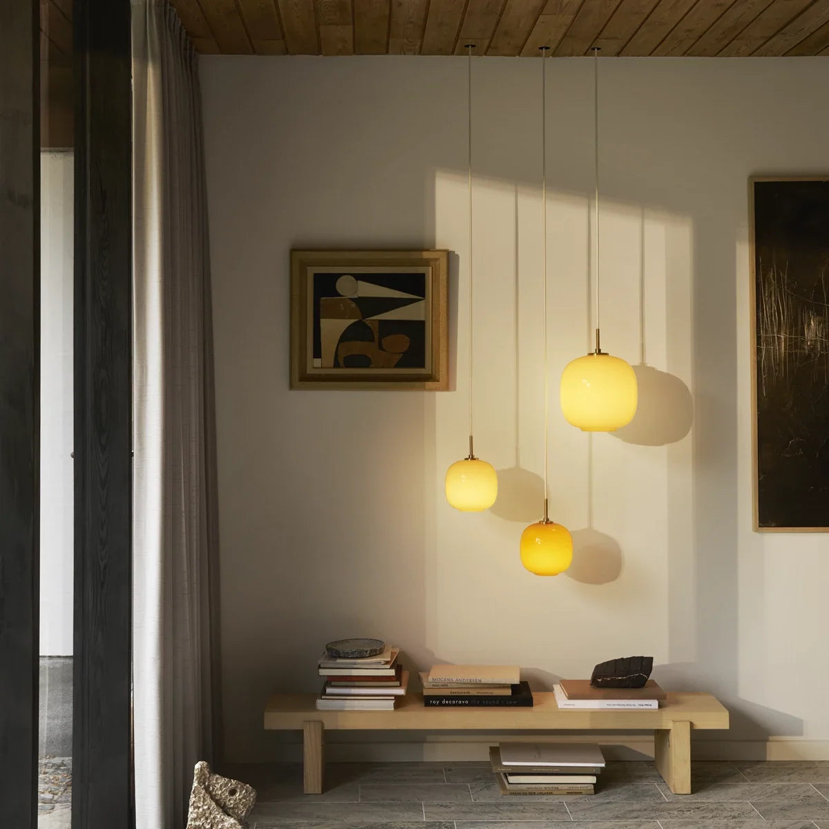 VL 45 Radiohus pendants in amber and pale yellow glass hung at different heights over a low bench