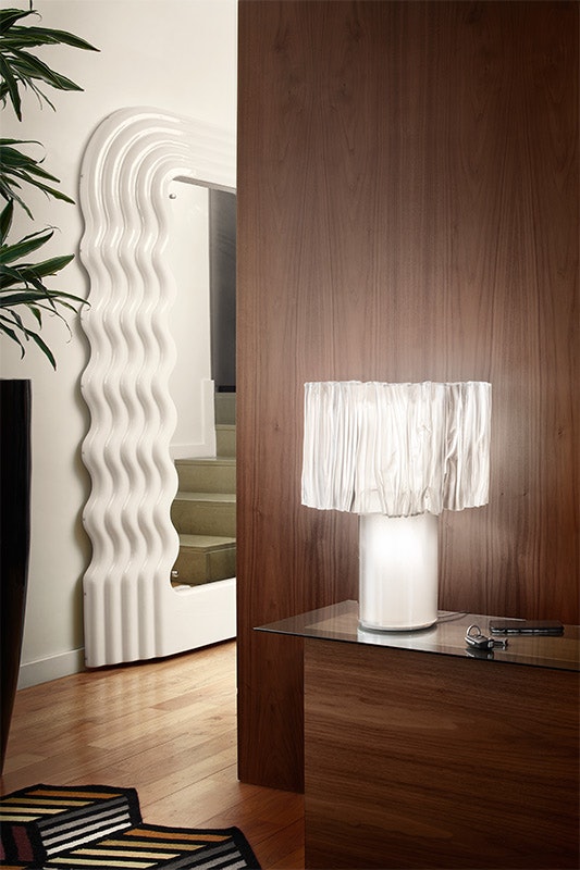 Slamp Accordeón Table lamp with pleated white diffuser on a glass side table in a living room
