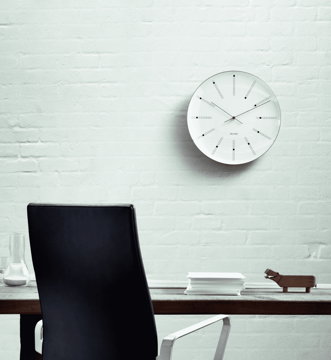 Bankers wall clock by Arne Jacobsen in white, black and red hanging on a wall