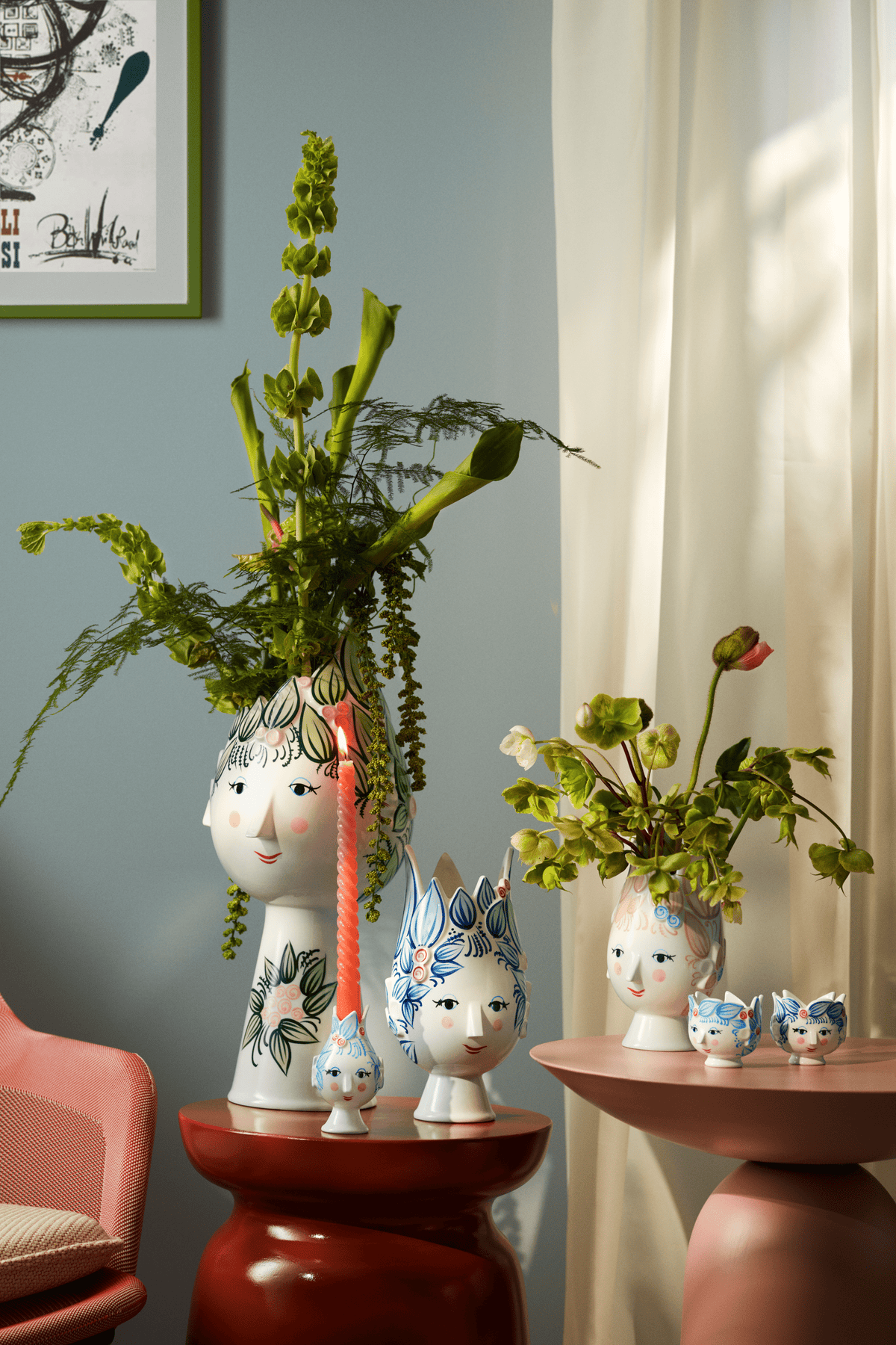 Wiinblad face vases of several sizes with green stems on red side tables in a living room