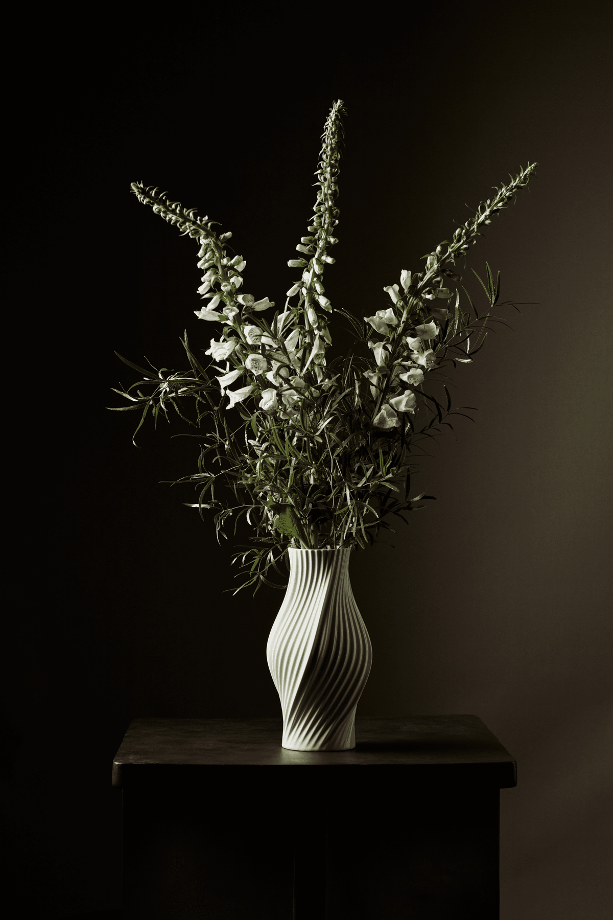 White Twist vase H31 cm by Lyngby Porcelæn with tall stems of foxglove and foliage on a dark wooden stand